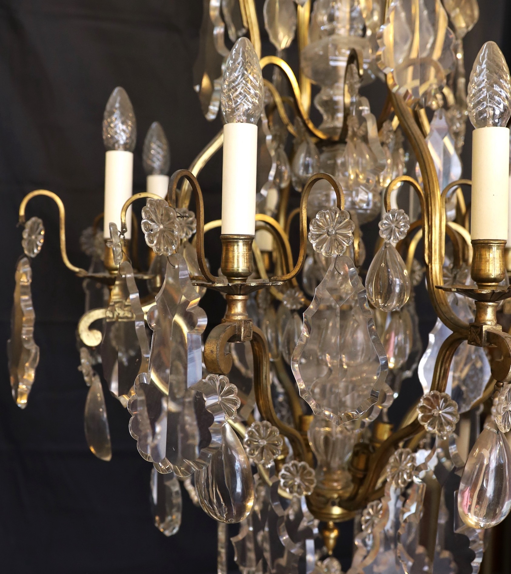 An early 20th century French bronze and cut glass twelve light chandelier, hung with tear, lozenge and flowerhead shaped drops, drop 114cm. width 72cm